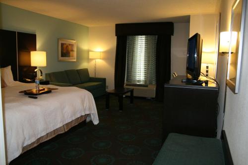 a hotel room with a bed and a couch and a television at Hampton Inn Shreveport-Airport in Shreveport