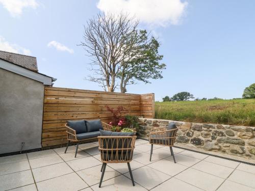 a patio with a couch and chairs and a fence at Y Beudy in Caernarfon