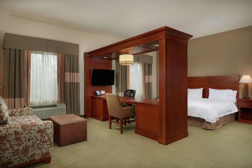 Habitación de hotel con cama con dosel y escritorio. en Hampton Inn and Suites Salem, en Salem