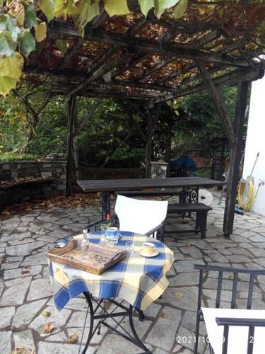 a table and chairs on a patio with a pergola at Άνετος χώρος με parking, αυλή και θαυμάσια θέα in Makrinítsa