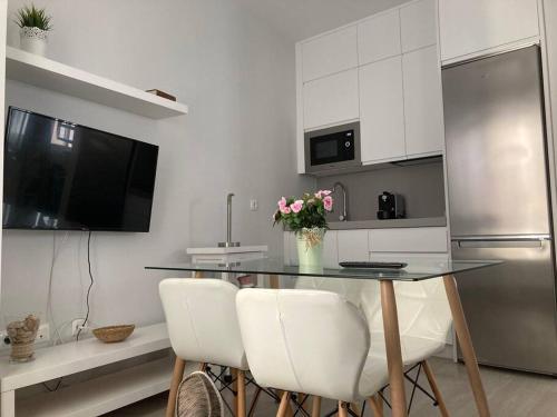 een keuken met een tafel met stoelen en een koelkast bij Apartamento Rota Progreso 5 in Rota