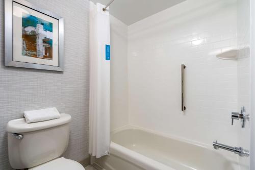 a white bathroom with a toilet and a bath tub at Hampton Inn - Springfield in Springfield