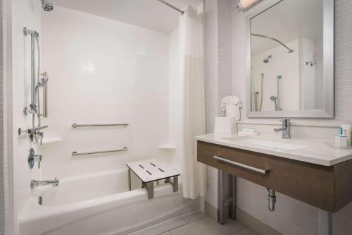 La salle de bains blanche est pourvue d'une baignoire, d'un lavabo et d'une douche. dans l'établissement Hampton Inn - Springfield, à Springfield