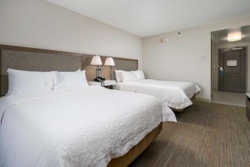 two beds in a hotel room with white sheets at Hampton Inn - Springfield in Springfield