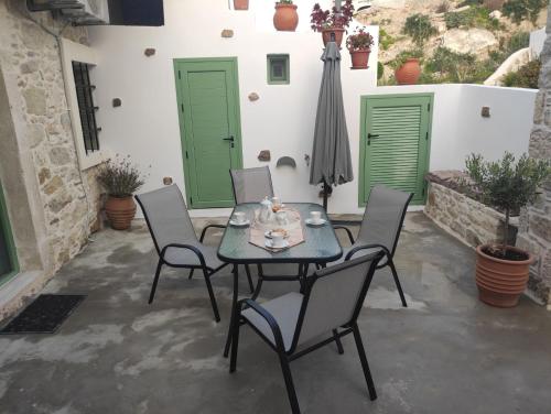 a patio with a table and chairs and green doors at La maison d Aspasia in Kamilari