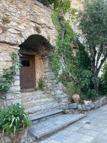 - un bâtiment en pierre avec une porte et des escaliers en bois dans l'établissement Les Matelles : charmant logement en pierres, à Les Matelles