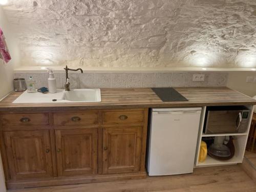 une cuisine avec un évier et un réfrigérateur blanc dans l'établissement Les Matelles : charmant logement en pierres, à Les Matelles