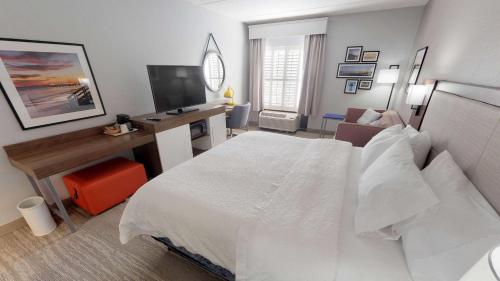 a bedroom with a bed and a desk with a television at Hampton Inn St. Simons Island in Saint Simons Island