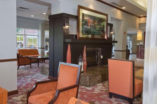 a living room with a fireplace and chairs at Hilton Garden Inn Starkville in Starkville