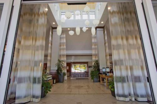 a lobby of a hotel with a hallway with plants at Hilton Garden Inn Starkville in Starkville