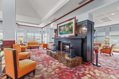a living room with a fireplace and orange chairs at Hilton Garden Inn Starkville in Starkville
