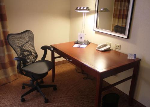 a desk in a hotel room with a chair and a lamp at Hilton Garden Inn Starkville in Starkville