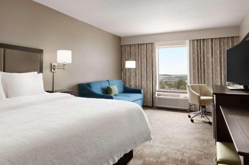 ein Hotelzimmer mit einem Bett und einem blauen Stuhl in der Unterkunft Hampton Inn Stow in Stow