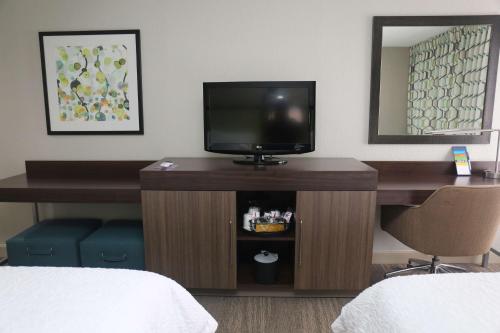 a room with a desk with a television and a mirror at Hampton Inn Sumter in Sumter