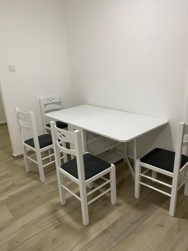 een witte tafel en stoelen met een witte tafel en vier stoelen bij Apartman Oaza in Nikšić