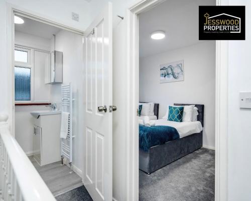 a white bedroom with a bed and a kitchen at Spacious 5 Bedroom, 3 Bath House by Jesswood Properties Short Lets For Contractors, With Free Parking Near M1 & Luton Airport in Luton