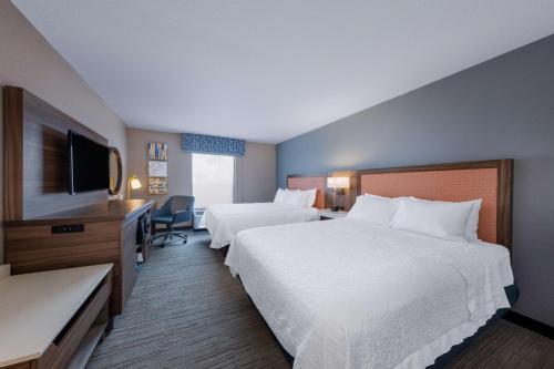 a hotel room with two beds and a flat screen tv at Hampton Inn Saint Robert in Saint Robert