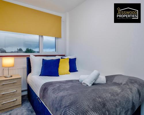 a bedroom with a bed with blue and yellow pillows at Spacious 5 Bedroom, 3 Bath House by Jesswood Properties Short Lets For Contractors, With Free Parking Near M1 & Luton Airport in Luton