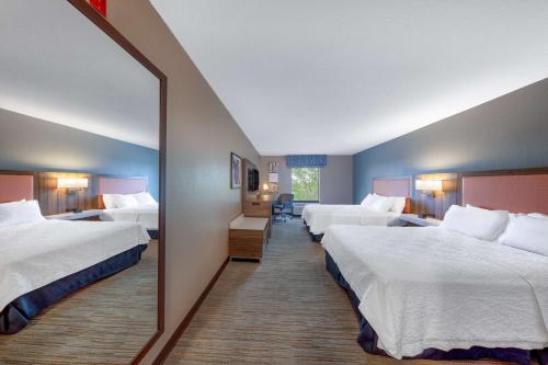 um quarto de hotel com três camas e um espelho em Hampton Inn Saint Robert em Saint Robert