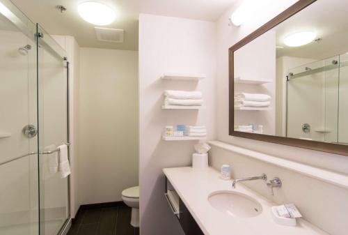 a bathroom with a sink and a mirror and a toilet at Hampton Inn Orange City in Orange City