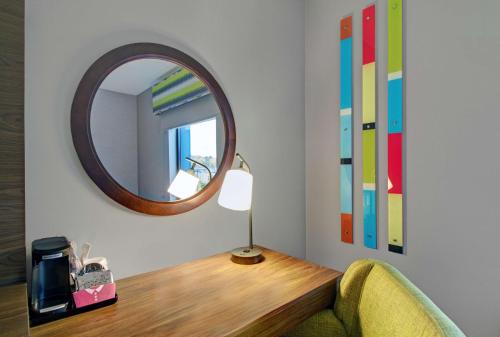 a mirror on a wall above a table with a chair at Hampton Inn & Suites by Hilton Syracuse Dewitt in East Syracuse