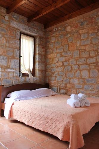 a bedroom with a bed in a stone wall at Lalloudes Seaside Accommodation in Éxo Nímfion