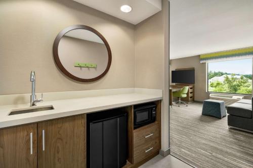a kitchen with a sink and a mirror and a living room at Hampton Inn & Suites Tacoma/Puyallup in Puyallup