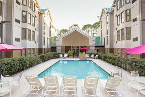 a swimming pool with white chairs and tables and umbrellas at Hampton Inn & Suites Tampa-North in Tampa