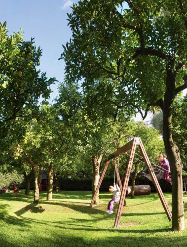 a little girl playing in a wooden frame in a park at Grand Hotel Excelsior Vittoria in Sorrento