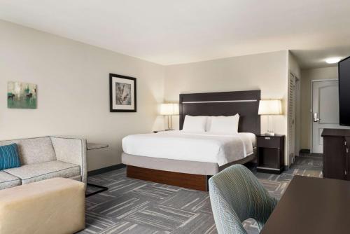 a hotel room with a bed and a couch at Hampton Inn New Albany in New Albany