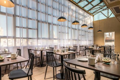 Un restaurante con mesas y sillas y grandes ventanales. en Up América Plaza, en Buenos Aires