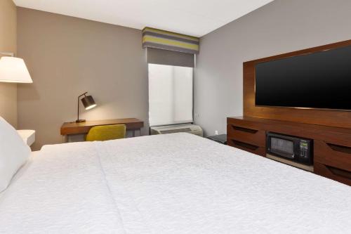 a hotel room with a bed and a flat screen tv at Hampton Inn Traverse City in Traverse City