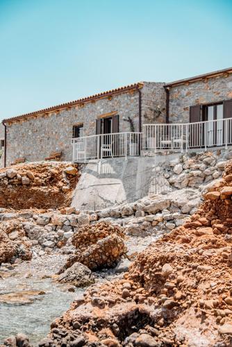 a building on a rocky hill with stairs and water at Petra Elounda Suites - Adults Only in Elounda
