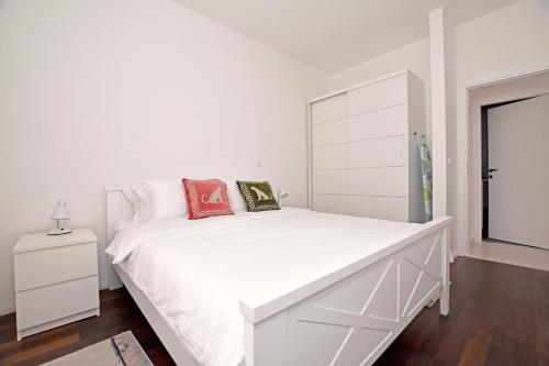- une chambre blanche avec un grand lit blanc et des oreillers rouges dans l'établissement Blue Harbour Luxury Apartment, Herceg Novi , Old Town, à Herceg-Novi