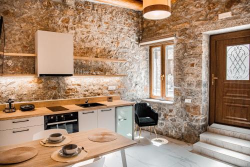 a kitchen with a wooden table and a stone wall at Petra Elounda Suites - Adults Only in Elounda