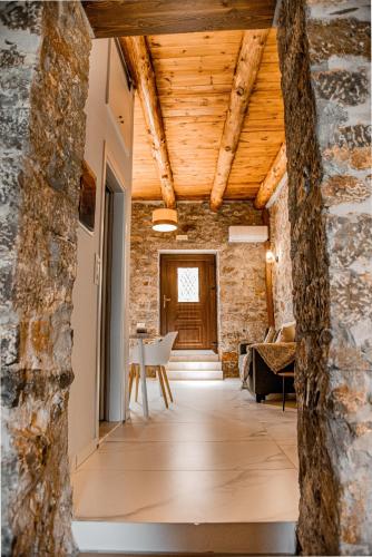 a room with a stone wall and wooden ceilings at Petra Elounda Suites - Adults Only in Elounda