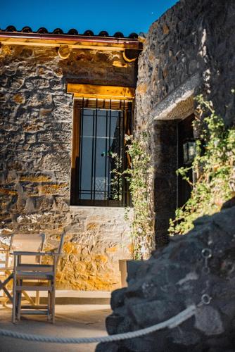 a chair in front of a stone building with a window at Petra Elounda Suites - Adults Only in Elounda