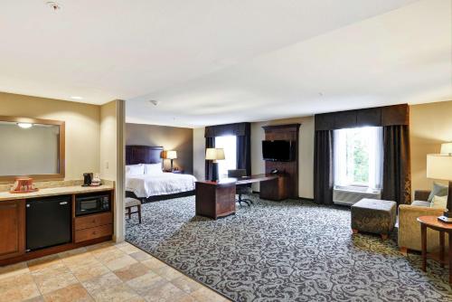 um quarto de hotel com uma cama e uma sala de estar em Hampton Inn and Suites New Hartford/Utica em New Hartford