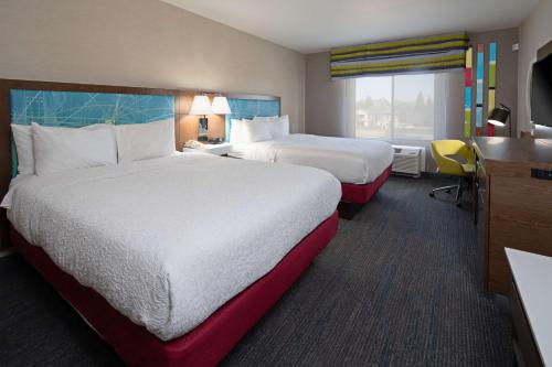 a hotel room with two beds and a desk at Hampton Inn Visalia in Visalia