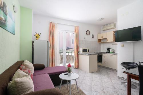 a living room with a purple couch and a kitchen at Apartmani Šuki in Trogir