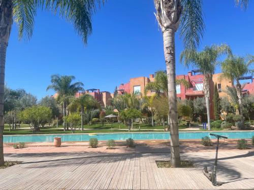 una piscina en un parque con palmeras en Résidence Le Vizir Center Rez de jardin, en Marrakech