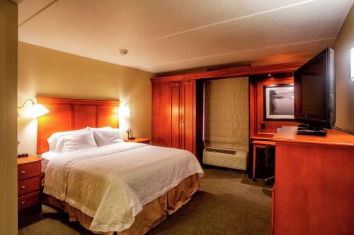 a hotel room with a bed and a flat screen tv at Hampton Inn Wheeling in Wheeling