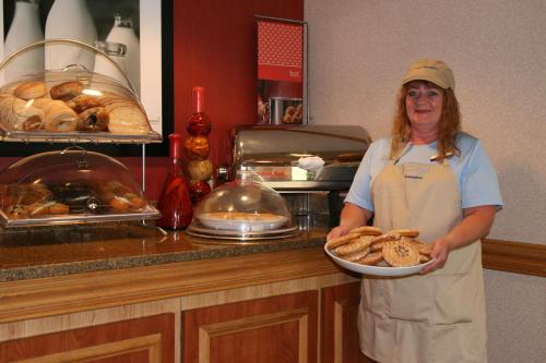 a woman in a bakery holding a plate of bread at Hampton Inn White River Junction in White River Junction