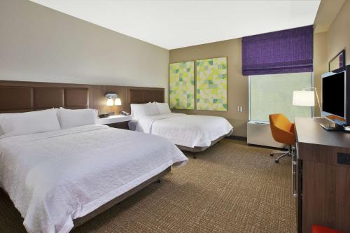 a hotel room with two beds and a flat screen tv at Hampton Inn White River Junction in White River Junction