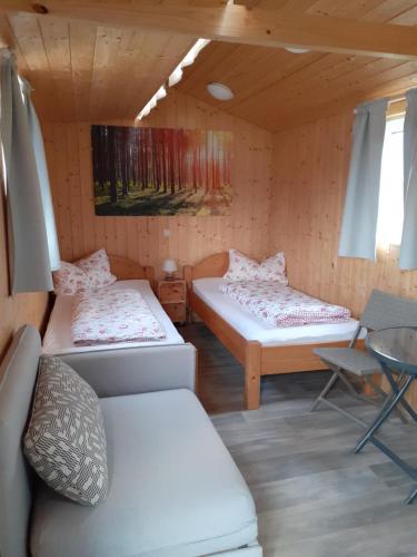Habitación con 2 camas, sofá y mesa. en Schlafwagen Beachvolleyball, en Xanten