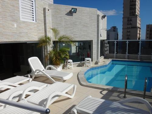 a swimming pool with lounge chairs next to a building at Atlantico Flat Gonzaga in Santos