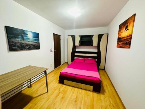 Dormitorio pequeño con cama rosa y banco en Apartament Roxi Costinesti, en Costinesti