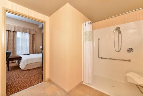 Hampton Inn & Suites by Hilton Edmonton International Airport في ليدوك: حمام مع دش وغرفة نوم