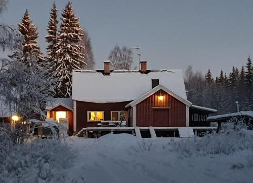 una casa cubierta de nieve con luces encendidas en Stationshuset Dalarna Apartments, en Sörsjön