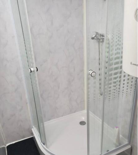 La salle de bains est pourvue d'une douche avec une porte en verre. dans l'établissement Apartament Roxi Costinesti, à Costinesti